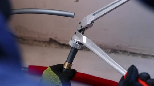 Metal Tool Connects Gray Pipe to Plumbing Fixture