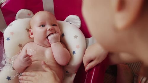 Mother Bathes Her Baby in Pink Bathtub Top View