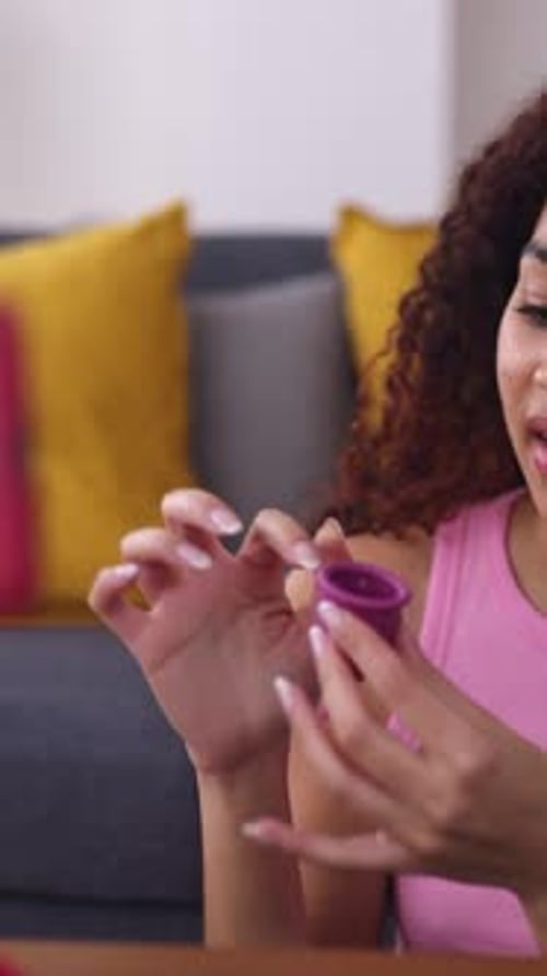 Adolescente que sostiene la copa menstrual mientras graba un vídeo tutorial en casa