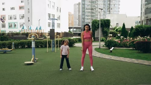 Mother and Daughter Workout Together in Urban Park During Sunny Day