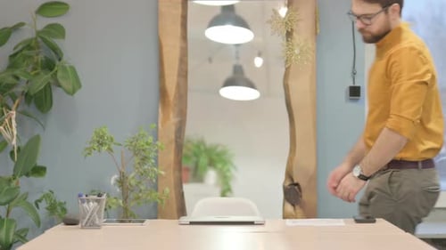 Man Opens Laptop at Office Desk