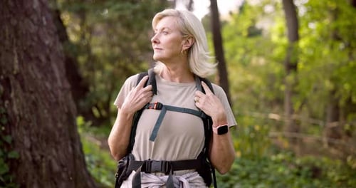 Blonde Woman Hiking in Green Forest with Backpack