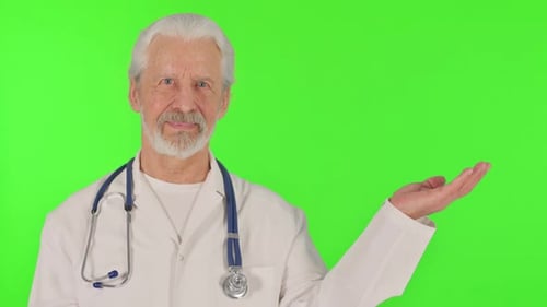 Portrait of Senior Doctor Showing Copyspace on Green Background