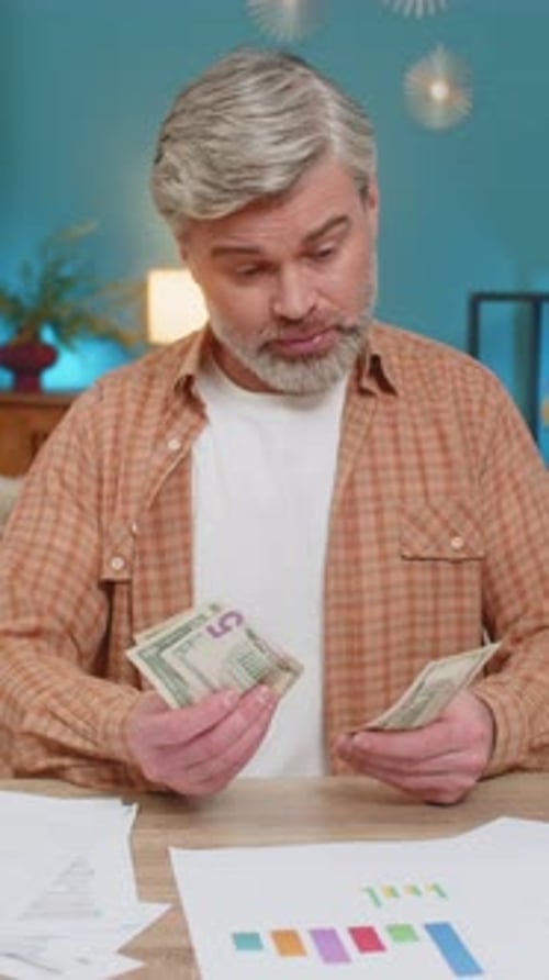 Man Looks at Bills, Counting Cash at Desk