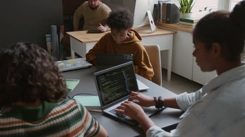 Diversos estudiantes que trabajan en tareas de codificación durante la clase de TI
