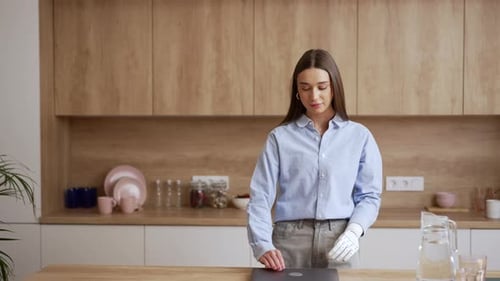 Young Woman Opens Laptop in Modern Kitchen