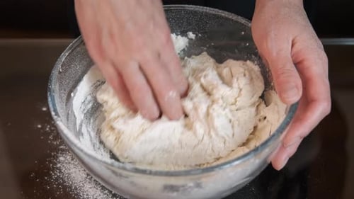 Hands Kneading Dough in Bowl Close Up