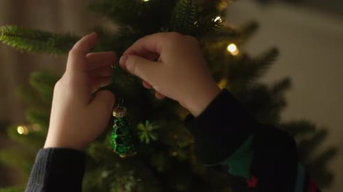 Child Decorates Christmas Tree with Ornament