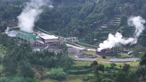 Drone view of a geothermal energy station in a mountainous area, producing clean electricity.