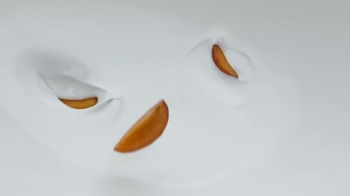 Ripe Apricot Pieces Falling on Creamy Yogurt in Super Slow Motion Close Up