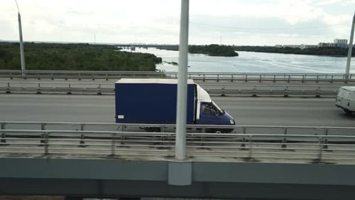 Cars and Trucks Driving on a Bridge Over River
