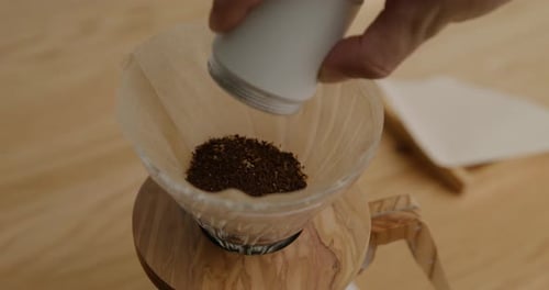 Preparing beans to brew coffee in a V60, tight shot with close up on ground beans being poured into