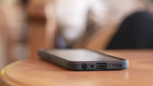 Hand Puts Smartphone Down, Picks it Up Again