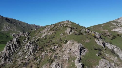 Aerial: Picturesque high green grass plateau in rugged mountain range