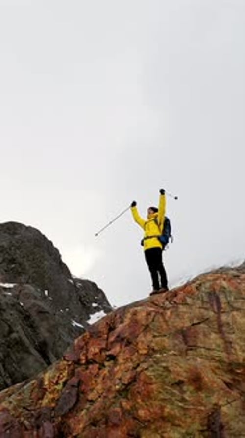 Hiker Celebrating Reaching the Summit with Arms Raised in Snowy Mountain Landscape