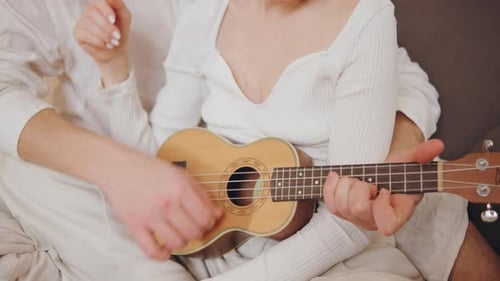 Happy Couple Playing Ukulele Together on Cozy Sofa