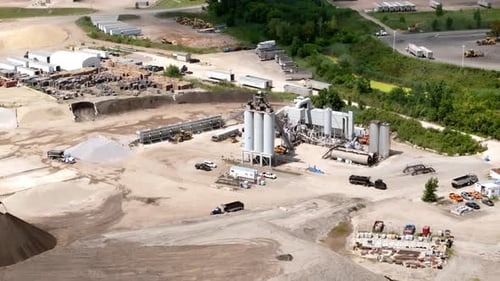 Aerial Drone View of an Industrial Cement and Asphalt Plant with Silos Conveyors and Trucks