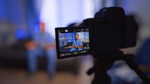 Man wearing blue uniform talking on the display of a modern camera. Close up. Vlogging concept.