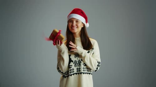 Woman in Santa Claus Hat Hold Christmas Gift on Gray Isolated Studio Background