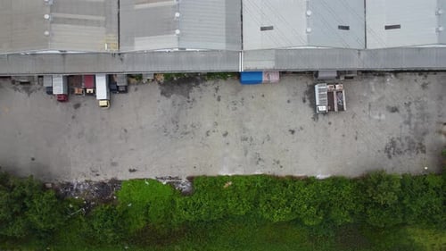 Aerial view of a goods distribution warehouse lined up with goods trucks parked in front of the ware