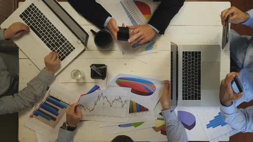 Top View to Male and Female Arms of Coworkers Plan a Future Project Sitting at Table Group of