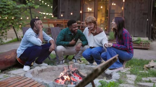 Friends Laughing Around Campfire in Nature Setting