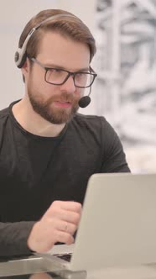 Adult Man with Headset Talking with Customers Online in Call Center, vertical