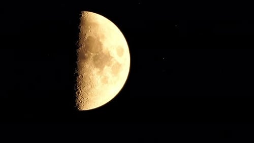 Zeitraffer Ein glühender goldener Halbmond, von der Erde aus gesehen durch die Atmosphäre vor einem Sternenhimmel
