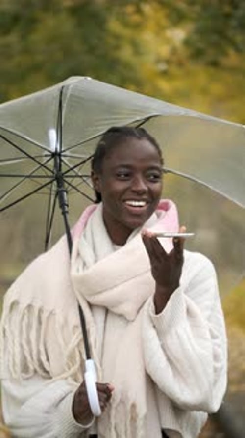 Woman Using Phone Under Umbrella in Autumn Park