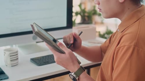 Young Adult Using Tablet and Stylus at Desk