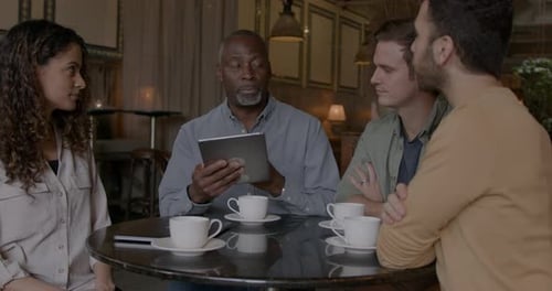 Group of Business People having Casual Meeting in Cafe using Digital tablet
