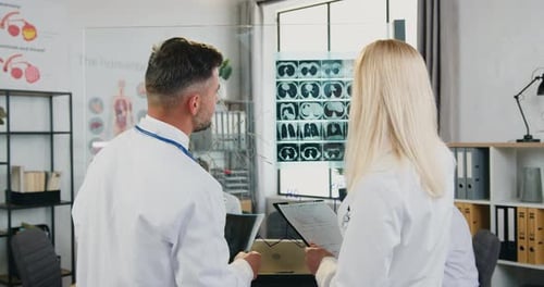 Professional man and woman doctors which learning patient's x-ray and discussing treatment in clinic