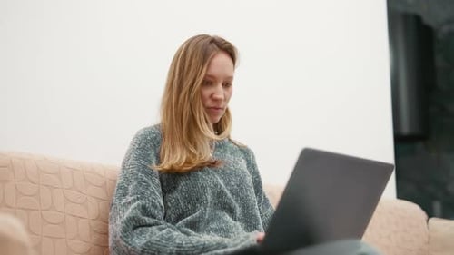 Young Woman Works on Laptop Sitting on Couch