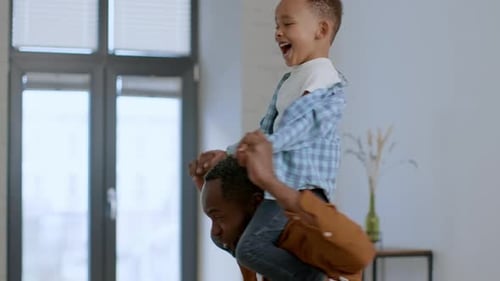 Loving Happy African American Father Riding His Cute Little Son on Shoulders Boy Laughing Tracking