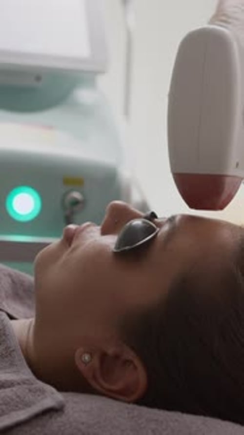 Woman Receiving Facial Laser Treatment in Clinic