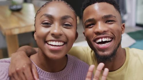 Smiling Couple Waving at Camera Indoors