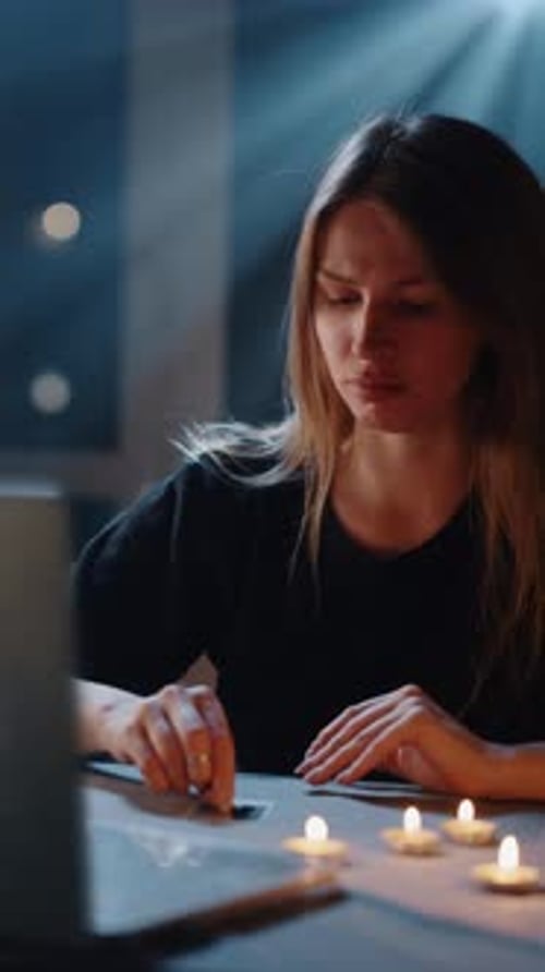 Woman With Candles Reads Tarot Cards at Table