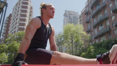 Starker Mann, der beim Training im Freien L-Sit auf Parallelstangen hält