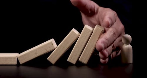 effet domino lent, gros plan, main, arrêt de la main pour faire tomber l'icône de l'employé. Concept en cas de chute d'activité