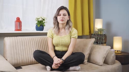 Serious Young Woman Sitting on Sofa Indoors