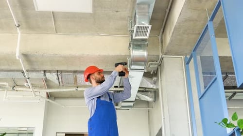 Man Installs Ventilation System in Modern Office