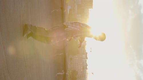 Young Man Breakdancing on City Rooftop at Sunset