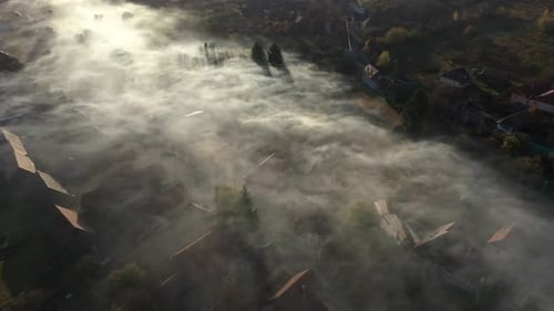 Aerial View of Morning Mist Over Village. House Roofs Raising from Clouds