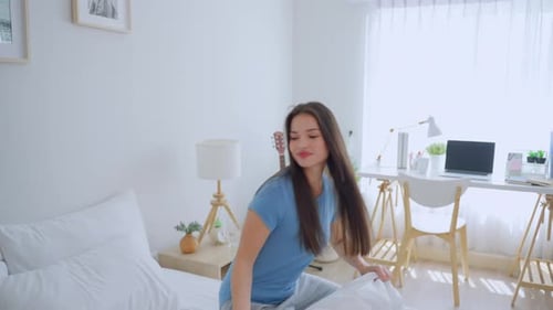 Woman Making Bed in Cozy Bedroom