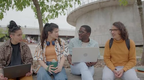 Company of College Friends Discussing Study Day Outdoors in the Park