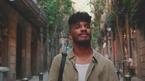 Close up, young smiling man walks along the narrow street of the old city and looks around