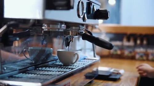 Close up view of workers hands that puts cup to coffee machine