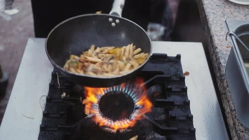 Chef Cooking with Fire in a Frying Pan at a Street Food Festival