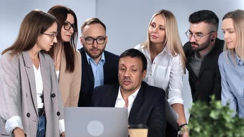 Diverse Team Collaborating on Laptop in Modern Office
