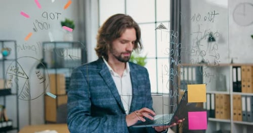 Smiling Young Man Works on Laptop in Office